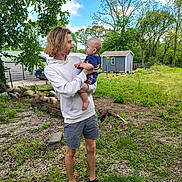 Zaidyn joined the competition — help win amazing prizes! baby, child, cloud, daylight, face, fence, footwear, grass, greenery, holding, hoodie, interaction, nature, outdoor, person, rocks, shed, shorts, sky, tree