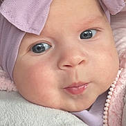 Layla is registered to the contest to win money with this photo: baby, infant, face, blue_eyes, pink_clothing, purple_headband, hood, zipper, blanket, car_seat, closeup, cute, child, soft_texture, warm, pout, expression, person, portrait, indoors