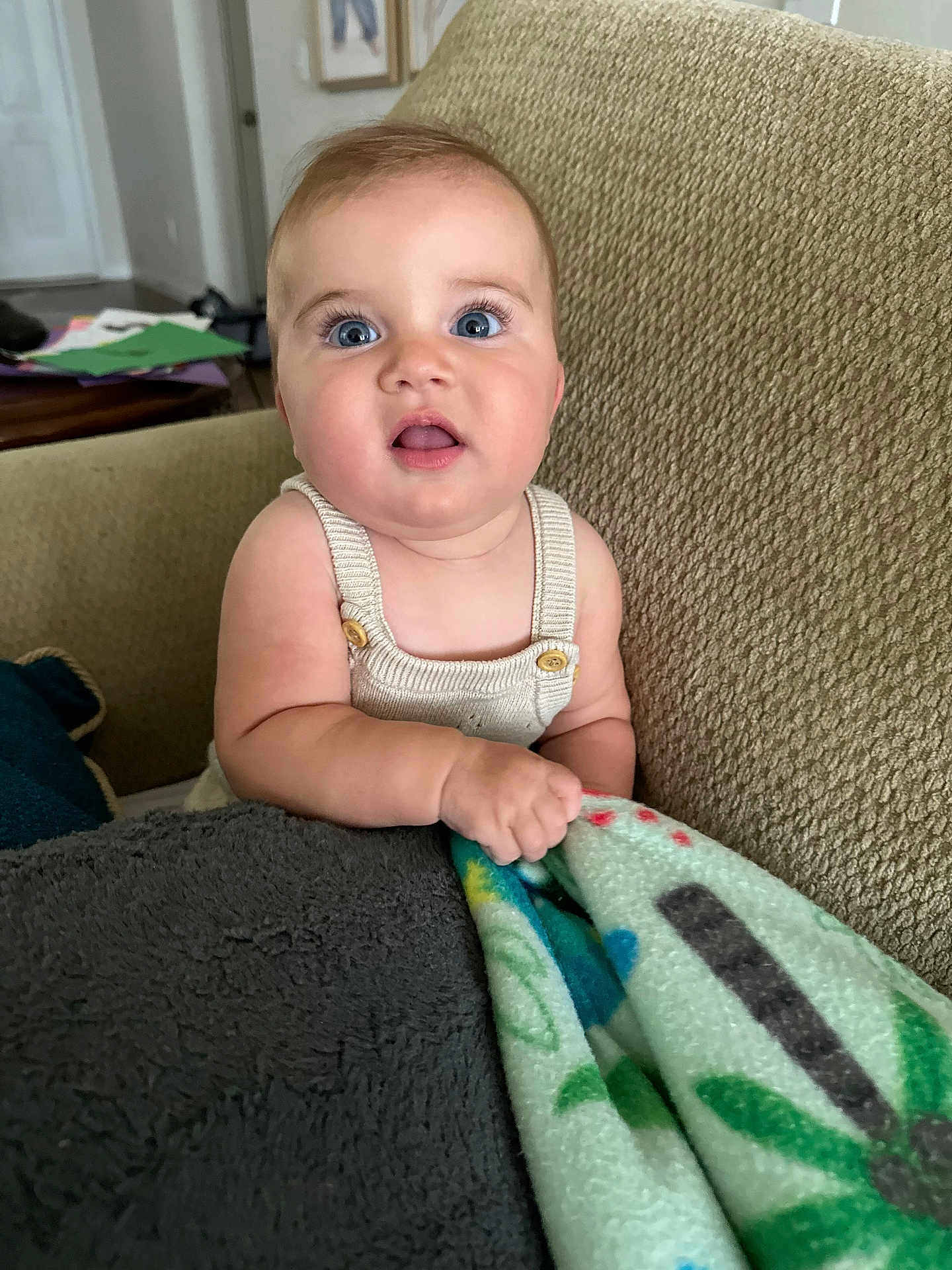 Gianna is registered to the contest to win money with this photo: baby, child, infant, blue_eyes, blanket, couch, indoor, person, portrait, cute, curious, chubby_cheeks, knit_clothing, texture, comfort, home, seated, hand, expression, furniture