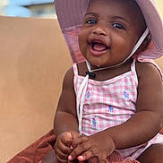 Xolani is registered to the contest to win money with this photo: baby, child, smiling, hat, pink, outdoor, towel, clothing, cute, happy, portrait, skin, face, hand, sunhat, infant, sitting, young, daytime, background