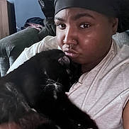 Jinx joined the competition — help win amazing prizes! affection, black_cat, black_fur, bonnet, cat, close_up, comfortable, couch, cozy, facial_expression, feline, home, indoor, nose_ring, person, pet, relaxed, snuggling, whiskers, white_shirt