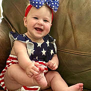 Helena joined the competition — help win amazing prizes! baby, child, smiling, happy, infant, headband, bow, stars, stripes, red, white, blue, clothing, sitting, barefoot, cute, portrait, indoor, couch, leather