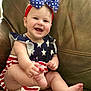 baby, child, smiling, happy, infant, headband, bow, stars, stripes, red, white, blue, clothing, sitting, barefoot, cute, portrait, indoor, couch, leather