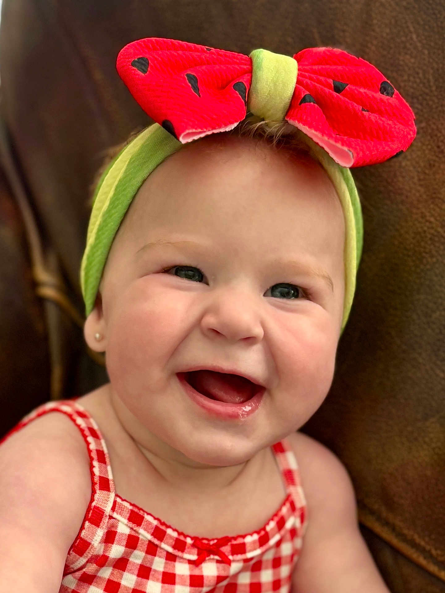 Helena is registered to the contest to win money with this photo: baby, infant, smiling, headband, bow, red, green, checkered_dress, cute, happy, portrait, face, child, cheerful, closeup, skin, earring, sitting, indoor, background