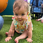 Hollie is registered to the contest to win money with this photo: baby, child, crawling, grass, playground, outdoor, colorful_clothing, stroller, toy, infant, smiling, person, cute, young_child, sunlight, happy, greenery, feet, hands, playtime