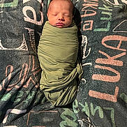 Luka is registered to the contest to win money with this photo: newborn, baby, swaddled, sleeping, blanket, face, infant, cozy, soft, resting, child, wrapped, text_pattern, fabric, indoors, cute, peaceful, portrait, human, young