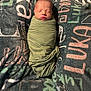 newborn, baby, swaddled, sleeping, blanket, face, infant, cozy, soft, resting, child, wrapped, text_pattern, fabric, indoors, cute, peaceful, portrait, human, young