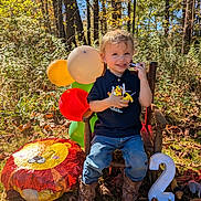Jaxson joined the competition — help win amazing prizes! child, toddler, boy, smiling, balloons, toys, wooden_chair, autumn_leaves, grass, outdoor, forest, sunlight, jeans, boots, number_2, celebration, birthday, happy, nature, playful