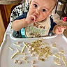 baby, high_chair, bib, food, snacks, rice, baby_food, kitchen, table, floor, child, indoor, person, cute, messy, hand, face, sitting, expression, young