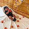 baby, basketball, miniature_basketball, baby_clothing, black_hat, white_blanket, mini_basketball_hoop, sports_theme, indoor, child, infant, toy, playful, sporty, floor, background, person, cute, sitting, black_outfit