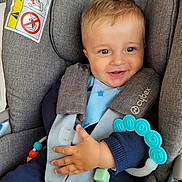 Timéo participe au concours pour gagner de l'argent avec cette photo : baby, child, car_seat, teething_toy, smile, happy, blue_clothing, seat_belt, infant, cute, indoor, face, hand, toy, safety, child_seat, blue, fabric, person, closeup