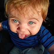 Shawn is registered to the contest to win money with this photo: toddler, child, blue_eyes, tongue_out, striped_shirt, dinosaur_pants, close_up, playful, sunlight, face, hair, person, smile, cute, baby, expression, warm_light, casual_clothing, indoor, portrait