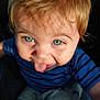 toddler, child, blue_eyes, tongue_out, striped_shirt, dinosaur_pants, close_up, playful, sunlight, face, hair, person, smile, cute, baby, expression, warm_light, casual_clothing, indoor, portrait