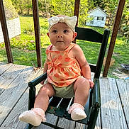 Paisley joined the competition — help win amazing prizes! baby, child, girl, bow, dress, rocking_chair, wooden_porch, outdoor, greenery, sunny, grass, trees, fence, cute, infant, socks, smiling, person, summer, daytime