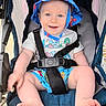 baby, child, infant, smiling, happy, portrait, stroller, seated, sun_hat, blue_clothing, harness, safety_belt, bare_feet, outdoor, daylight, close_up, face, playful, colorful, photography