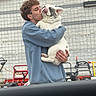 Chubby is registered to the contest to win money with this photo: man, dog, french_bulldog, holding, kissing, blue_sweatshirt, outdoor, wall, lawn_equipment, playful, pet, affection, curly_hair, candid, window_frame, vehicle_interior, tongue_out, human_animal_interaction, casual_clothing, daytime