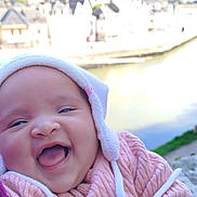 Youna participe au concours pour gagner de l'argent avec cette photo : baby, smiling, happy, infant, face, hat, pink_sweater, tongue_out, outdoor, river, water, blurred_background, person, closeup, cute, child, winter_clothing, nature, daylight, scenic