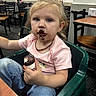 Nova joined the competition — help win amazing prizes! toddler, child, chocolate, food, high_chair, pink_shirt, blue_jeans, messy_hair, indoor, restaurant, table, chair, face, messy_face, snack, curious, person, young_child, sitting, casual