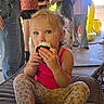 toddler, child, cupcake, food, eating, pink_tank_top, floral_leggings, blue_eyes, indoor, people, play_structure, cushion, casual_clothing, messy_nose, sitting, party, background, fun, young_child, light