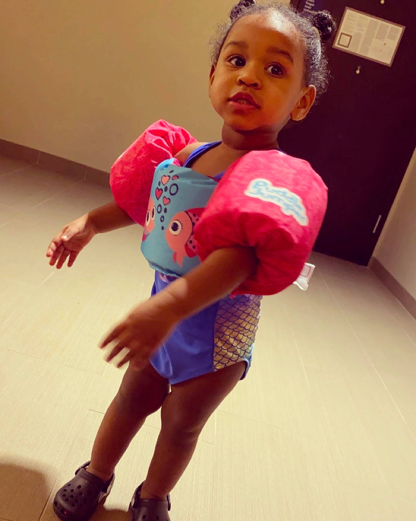 Devynn is registered to the contest to win money with this photo: baby_toddler_clothing, elbow, face, finger, flooring, gesture, happy, head, human_leg, joint, knee, one_piece_garment, person, pink, skin, sleeve, t_shirt, thigh, thumb, toddler