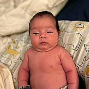 Juliano is registered to the contest to win money with this photo: baby, infant, mittens, diaper, cushion, animal_print, face, skin, expression, newborn, portrait, indoor, child, cute, resting, soft, blanket, comfort, young, human