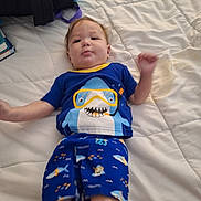 Hudson joined the competition — help win amazing prizes! baby, child, infant, portrait, lying_down, bed, bedroom, quilt, blue_clothing, shark_shirt, pajamas, smiling, face, arms, legs, red_hair, indoor, casual, playful, photography
