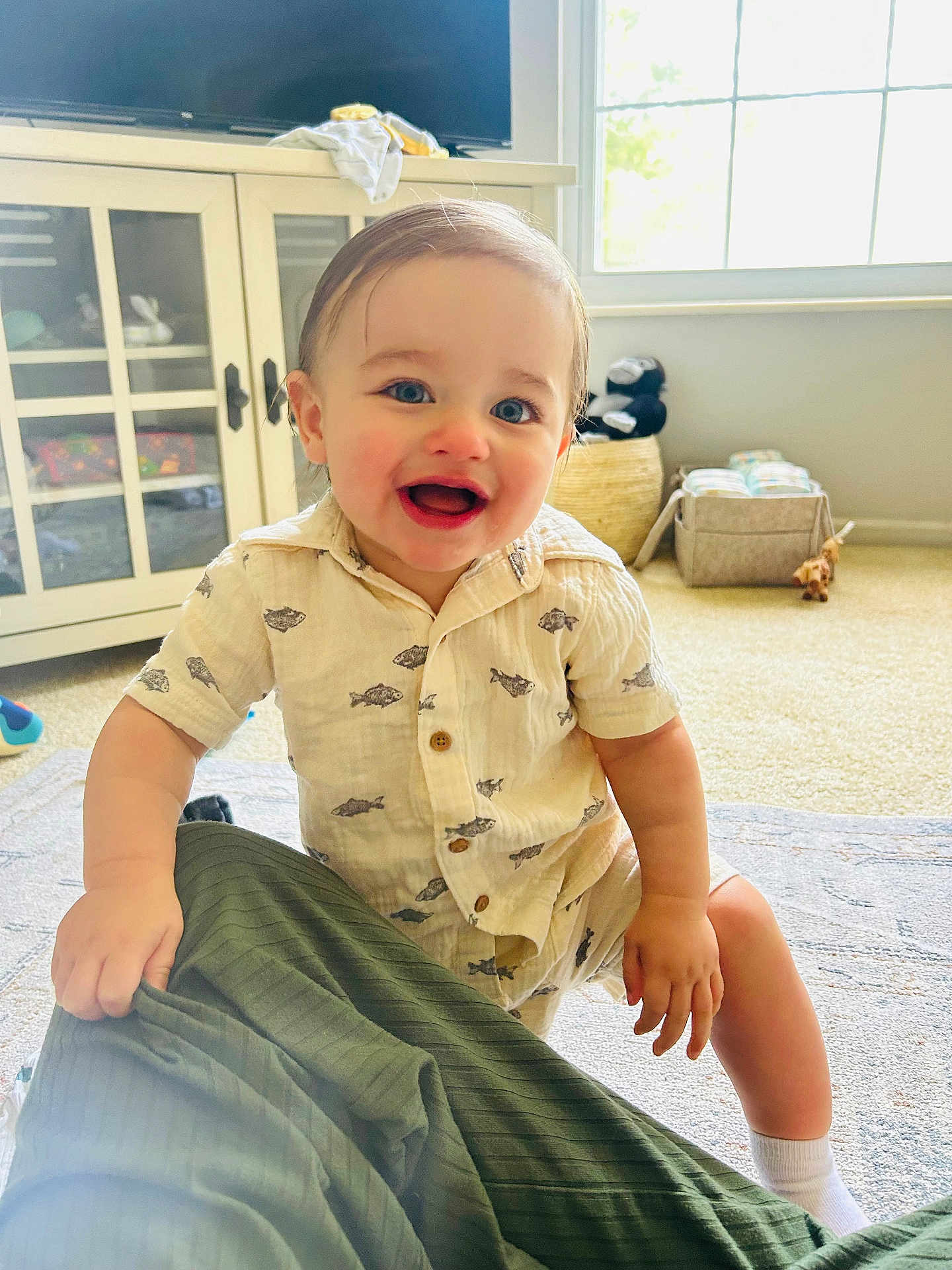 Daniel joined the competition — help win amazing prizes! toddler, child, smiling, indoor, carpet, cabinet, window, toy, clothing, person, happy, blue_eyes, short_sleeves, sock, furniture, room, daylight, holding, patterned_shirt, floor