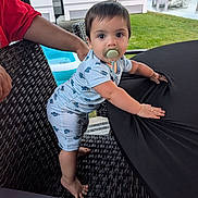 Kaiser joined the competition — help win amazing prizes! toddler, child, pacifier, blue_clothing, wicker_chair, black_tablecloth, outdoor, grass, pond, rv, adult_hand, curious, standing, baby, short_hair, daylight, backyard, table, person, summer