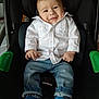 baby, child, car_seat, white_shirt, blue_jeans, blue_socks, smile, indoor, cute, infant, portrait, clothing, seatbelt, happy, person, young_child, casual, sitting, expression, cozy