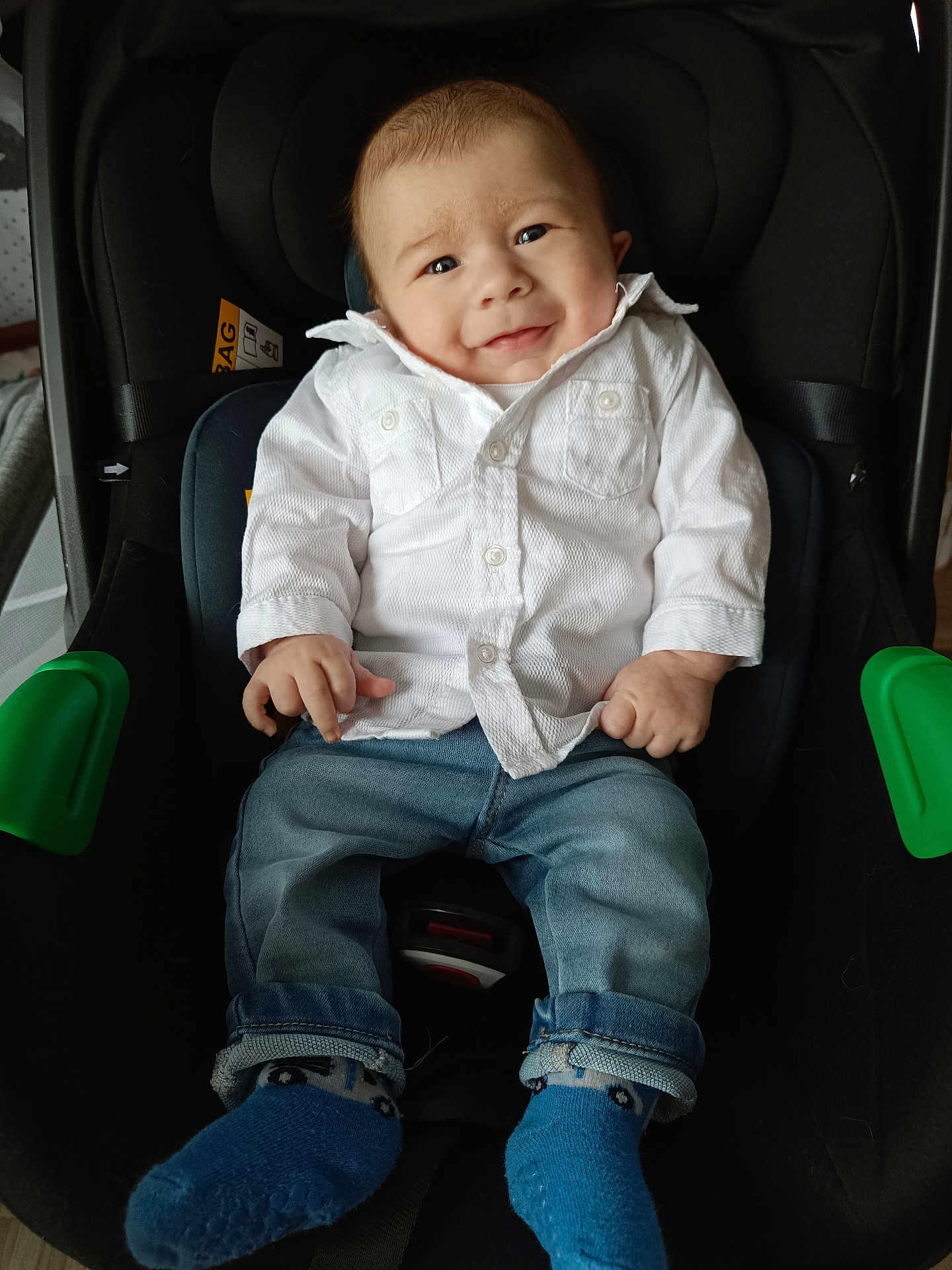 Nahel a rejoint le concours — aidez-le/la à gagner de superbes lots ! baby, child, car_seat, white_shirt, blue_jeans, blue_socks, smile, indoor, cute, infant, portrait, clothing, seatbelt, happy, person, young_child, casual, sitting, expression, cozy