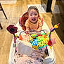 Alanna is registered to the contest to win money with this photo: baby, walker, toy, blanket, smiling, child, indoor, floor, wooden_floor, kitchen, happy, person, colorful, playtime, seat, infant, cute, clothing, face, furniture