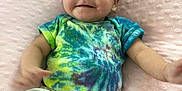 Alanna is registered to the contest to win money with this photo: baby, infant, smile, tie_dye_shirt, pink_pillow, soft_texture, cute, happy, child, clothing, sitting, indoors, person, portrait, young, face, skin, head, relaxing, comfortable