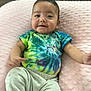 baby, infant, smile, tie_dye_shirt, pink_pillow, soft_texture, cute, happy, child, clothing, sitting, indoors, person, portrait, young, face, skin, head, relaxing, comfortable