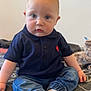 baby, blanket, blue_eyes, casual_clothing, child, curious_expression, cute, denim_pants, face, feet, hands, head, indoor, infant, navy_polo, plush_toy, portrait, sitting, socks, young_child