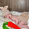 baby, blanket, bunny_ears, carrot_toy, child, cozy, crocheted, cute, diaper_cover, face, hand, infant, knitted_hat, leg, peaceful, pillow, resting, sleeping, soft_texture, wooden_background