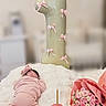 baby, balloon, birthday_cake, blanket, bouquet, candle, celebration, cute, decorations, festive, flowers, headband, indoor, infant, number_one, pink_clothing, pink_roses, portrait, sleeping, soft_texture