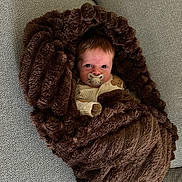 Henry joined the competition — help win amazing prizes! baby, infant, pacifier, blanket, brown_blanket, couch, fabric, texture, wrapped, snug, cute, face, head, eyes, lying_down, indoor, soft, comfort, person, newborn
