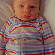 Oaklyn is registered to the contest to win money with this photo: baby, child, infant, face, striped_clothing, onesie, lying_down, portrait, serious_expression, soft_surface, person, young_child, sleepwear, colorful, cute, indoors, closeup, head, skin, calm
