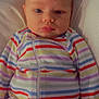 baby, child, infant, face, striped_clothing, onesie, lying_down, portrait, serious_expression, soft_surface, person, young_child, sleepwear, colorful, cute, indoors, closeup, head, skin, calm