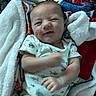 Kacee is registered to the contest to win money with this photo: baby, infant, blanket, onesie, smile, face, arm, hand, cozy, cute, expression, indoor, soft_texture, patterned_clothing, child, newborn, portrait, lying_down, warm, comfort