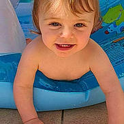 Alba participe au concours pour gagner de l'argent avec cette photo : toddler, child, pigtails, smiling, inflatable_pool, water, sunlight, brick_wall, window, outdoor, crawling, happy, skin, face, play, summer, cute, baby, hands, blue