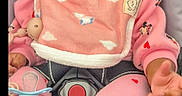 Nevaeh-Celeste joined the competition — help win amazing prizes! baby, infant, car_seat, pink_clothing, bib, pacifier, headband, curly_hair, mickey_mouse, indoor, child, person, cute, expression, seated, clothing, toy, accessory, closeup, face