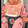 baby, infant, car_seat, pink_clothing, bib, pacifier, headband, curly_hair, mickey_mouse, indoor, child, person, cute, expression, seated, clothing, toy, accessory, closeup, face