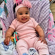 Nevaeh-Celeste is registered to the contest to win money with this photo: baby, infant, smiling, pink_clothing, headband, bow, blanket, toy, baby_seat, cozy, happy, cute, child, cheerful, indoors, soft_texture, person, footwear, hand, face