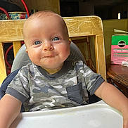 Reid is registered to the contest to win money with this photo: baby, blue_eyes, camouflage_shirt, child, cute, face, feeding, food, happy, high_chair, home, indoor, infant, messy_face, person, portrait, seated, smile, table, wooden_chair