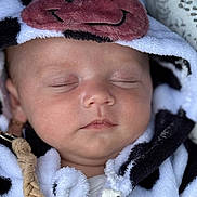Alix a rejoint le concours — aidez-le/la à gagner de superbes lots ! baby, sleeping, hood, blanket, cow_pattern, face, closeup, soft, cute, infant, child, peaceful, clothing, portrait, young, adorable, warm, cozy, fabric, resting