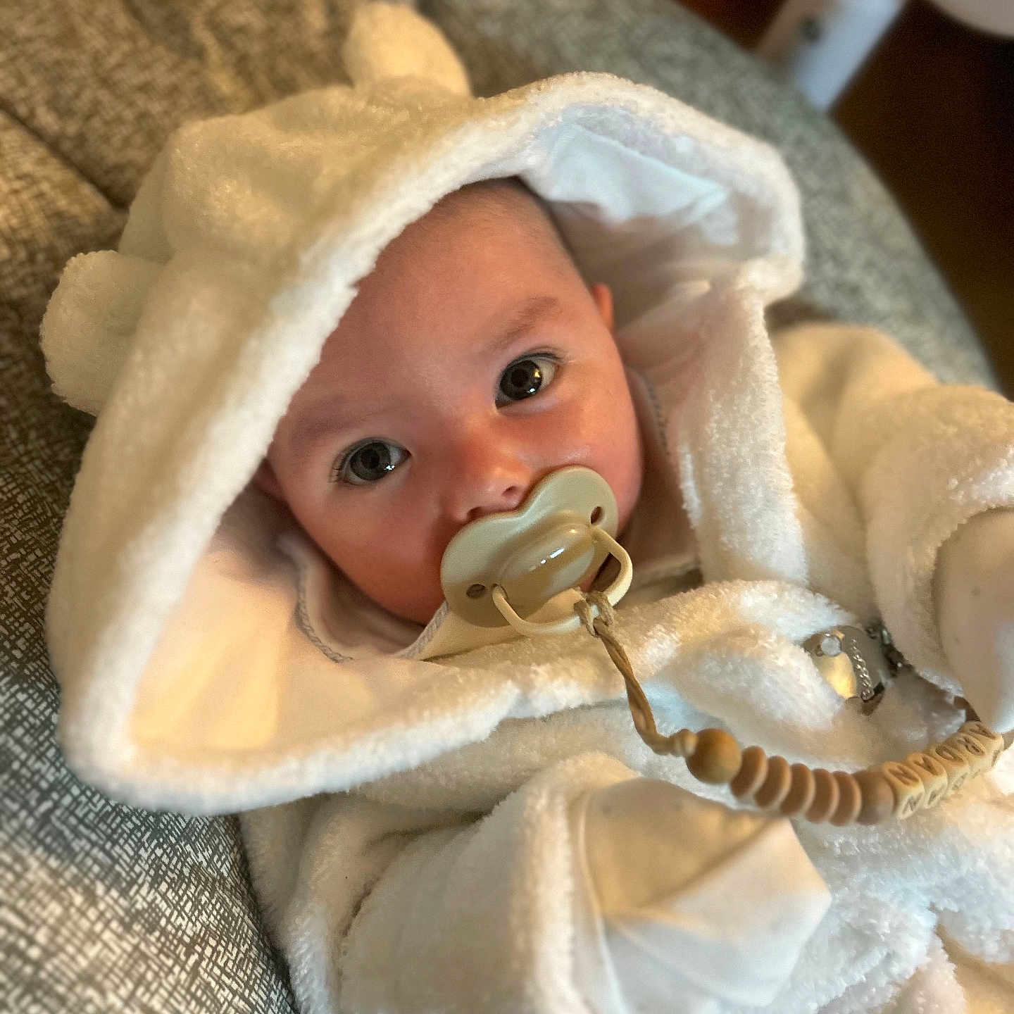 Ardán-John joined the competition — help win amazing prizes! baby, beaded_clip, big_eyes, child, close_up, cozy, cushion, cute, face, hood, indoor, infant, pacifier, portrait, resting, sleepwear, soft_texture, warm_clothing, white_clothing, young_child