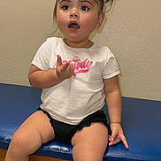 Bella joined the competition — help win amazing prizes! toddler, child, sitting, white_tshirt, black_shorts, bow, hair_accessory, blue_bench, curious_expression, indoor, colorful_shoes, pink, white_socks, short_hair, person, young_child, casual_clothing, looking_away, small_hands, bare_legs