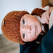 Jackson joined the competition — help win amazing prizes! baby, child, face, headwear, knit_hat, button, blue_eyes, skin, closeup, portrait, warm_colors, soft_texture, hand, clothing, indoors, infant, cute, young, expression, looking