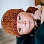 baby, child, face, headwear, knit_hat, button, blue_eyes, skin, closeup, portrait, warm_colors, soft_texture, hand, clothing, indoors, infant, cute, young, expression, looking